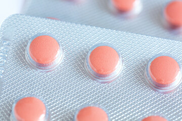 Orange-pink round pills in packaging close-up, medicines , top view