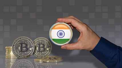 A hand holding a badge with the Indian flag in front of some bitcoins. Crypto currency concept.