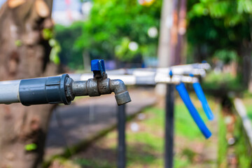 Line of public iron water blue faucet with blurry and soft focus backgroud at the city park