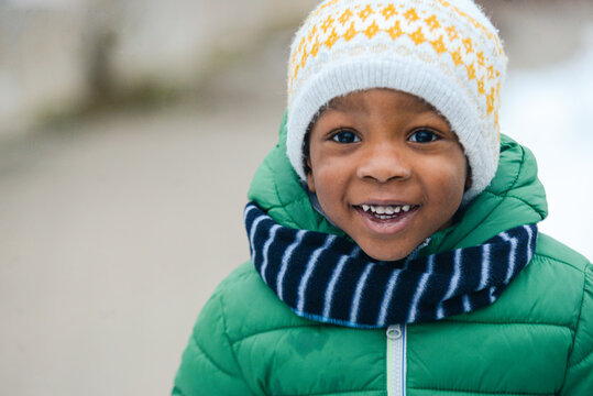portrait of smiling african american kid dressed warm with scarf and wool cap in winter outdoors