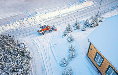 Snow removing with red tractor on the road. Suny winter day, Drone top view.