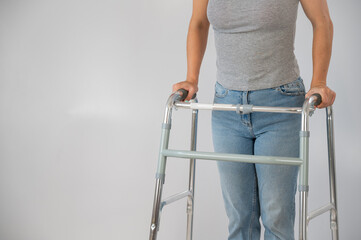 A woman is walking with a walker on a white background