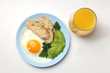 Plate of breakfast and glass of juice on white background