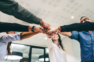 Modern businesspeople bringing their fists together in an office