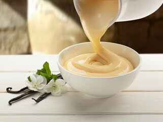 Crema de vainilla sobre tabla de madera y flor de vainilla. Vanilla cream on wooden board and vanilla flower.
