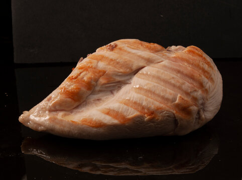  primer plano de pechuga de pollo a la plancha sobre fondo negro. grilled chicken breast close-up on black background.