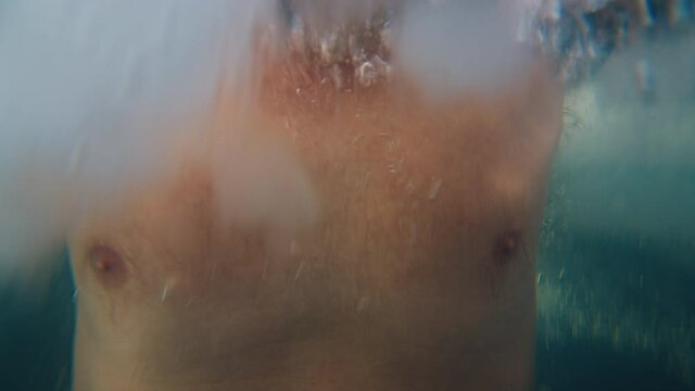 Winter swim. Young man swims in the winter lake. Splitted above and under view of the man swimming in the icy water