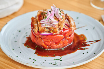 Red bell pepper salad garnished with tuna and onion and served on plate during lunch in restaurant.