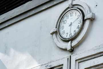 Close-up vintage and retro public city clock showing the time on the white wall ornament