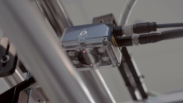 An industrial laser sensor on a conveyor detects the passage of a goods and enters into a database. Shot in motion. Closeup