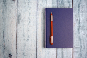 Blue notepad and ballpoint pen on a wooden background. Top view, flat lay