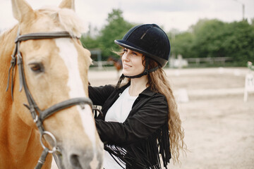 Fototapeta premium Portrait of riding horse with woman in black helmet