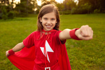 Brave girl in superhero cape in park - obrazy, fototapety, plakaty