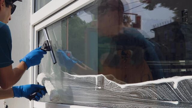 A professional cleaning service worker washes the windows with special foam and cleans them.