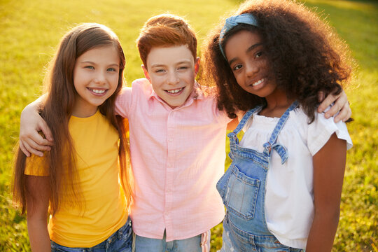 Company of diverse kids hugging in park