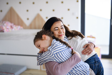 Happy small girls greeting senior grandmother indoors at home, hugging.