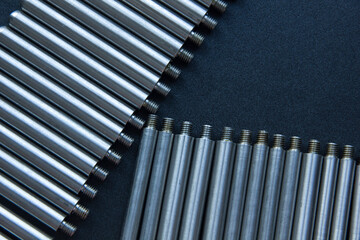 Rod, axis with thread on the table. Parts in a row at the factory.