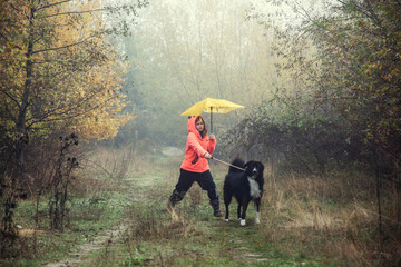 Girl with a dog walking in foggy weather in the forest - 479524935