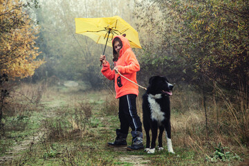 Girl with a dog walking in foggy weather in the forest - 479524936