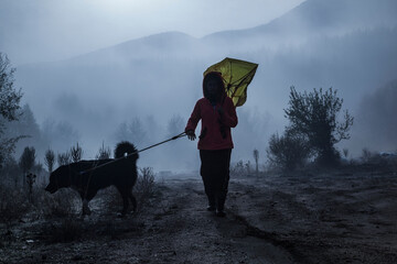 Girl with a dog walking in foggy weather in the forest - 479524943
