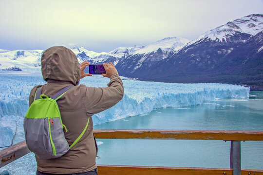A man, a tourist takes a  photo on smartphone at the reserve in Perito Moreno, a glacier in Patagonia. Ice blocks in El Calafate, Argentina, Los Glaciares National Park