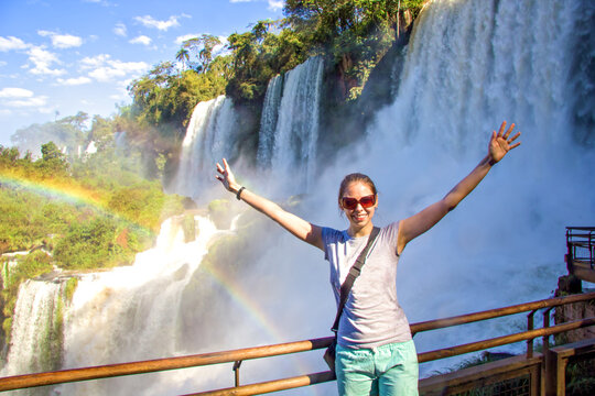 Tourist girl raise her hands towards the sun. Part of The Iguazu Falls seen from the Argentinian National Park. Border of Brazil and Argentina. National Park. South America, Latin America.