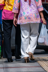 Two worker women holding a plastic bag, walking in the sidewalks together