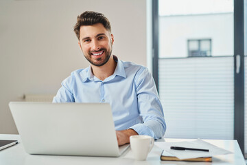 Portrait of young businessman smiling sitting by the desk