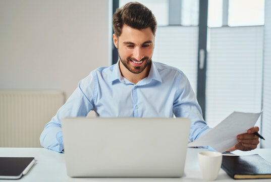 Smiling young man paying bills on laptop