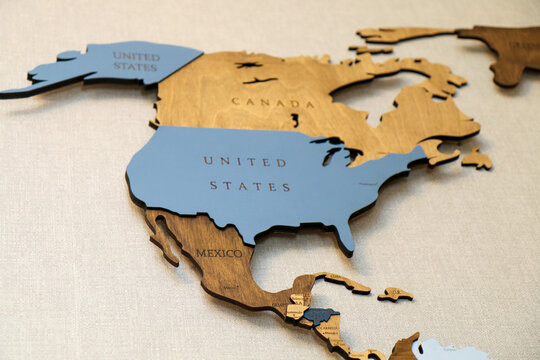 Wooden map of the world on the wall.  Mainland North America continent with the names of countries and capitals. Geographic concept of plywood, laser cutting.