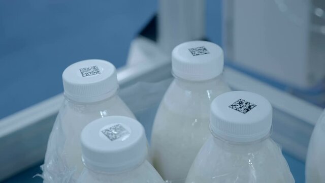 Group of white plastic milk bottles with qr codes pasted on their caps. Shot in motion. Closeup