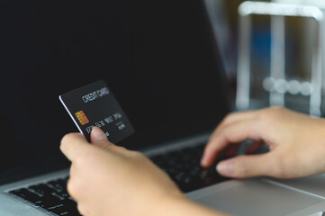 Close up woman hands holding credit card and using laptop shopping purchasing online. e-commerce, internet banking, checking balance, banking service, paying by credit card, making payment.