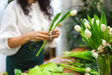 Obraz premium Attractive young woman florist is working in a flower shop.