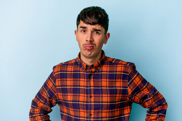 Young mixed race man isolated on blue background sad, serious face, feeling miserable and displeased.