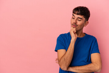 Fototapeta premium Young mixed race man isolated on pink background looking sideways with doubtful and skeptical expression.