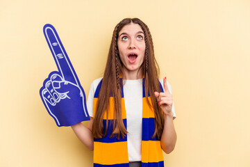 Young sports fan woman isolated on yellow background pointing upside with opened mouth.