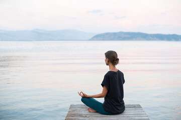 Beautiful woman practicing yoga near the sea, Young girl meditate at sunset, Harmony, meditation,...