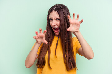 Young caucasian woman isolated on green background upset screaming with tense hands.