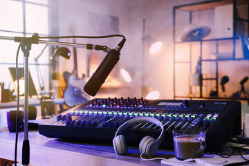 Microphone near table with professional mixing console in radio studio