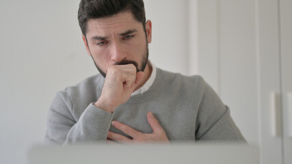 Close up of Young Man Coughing while using Laptop
