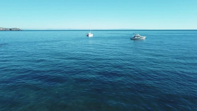 Yacht ship boat at Monte Argentario, Italy. Clear blue turquoise and calm seaside water at a scenic sand beach coast bay. 4K aerial drone air flight at tourist holiday destination on vacation island.