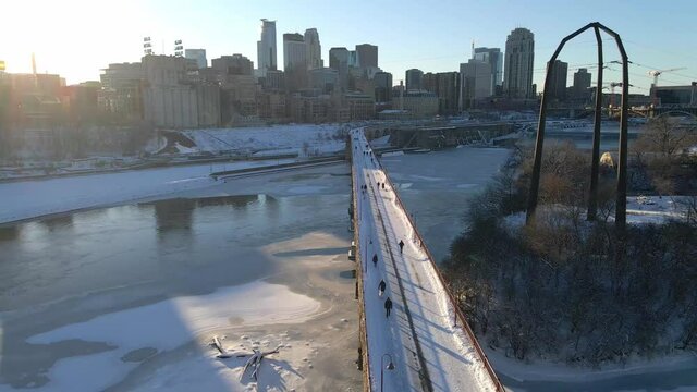 Aerial view of people at stone arch bridge crossing the mississippi river in Minneapolis with downtown view winter afternoon