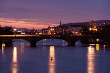 Fototapeta na wymiar Prague at night, view of the Vlatava river, reflection of night city lights, cityscape