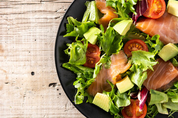 Salmon and avocado salad on rustic wooden table	
