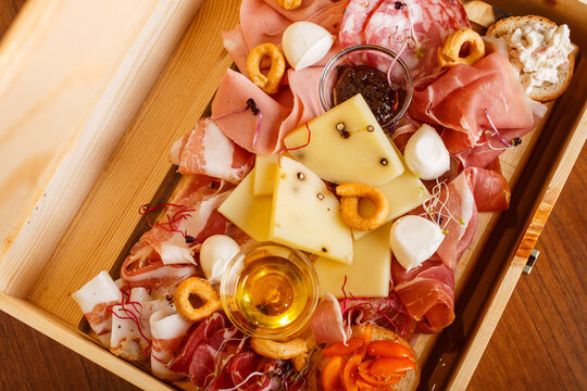 Tagliere di salumi e formaggi con miele, taralli e salse servito in un elegante cassetta di legno