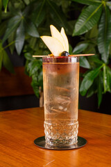 Cocktail fatto con gin infuso alla mela annurca e fico d'india, e tonica allo Yuzu Royal Bliss, poggiato su un tavolo di legno