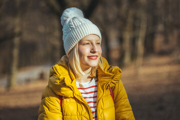 Portrait of a beautiful young woman with blonde hair enjoying autumn in the park. Fall season and cute walking girl. Young beautiful woman wearing winter clothing