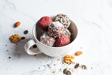 Raw vegan dessert. Energy balls. Truffles made from nuts, seeds, cocoa, dates and superfood powders, white marble background.