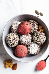 Raw vegan dessert. Energy balls. Truffles made from nuts, seeds, cocoa, dates and superfood powders, white marble background.