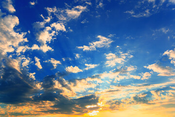 Dramatic sky with feather clouds. Sun's rays shine through clouds. Colorful background.